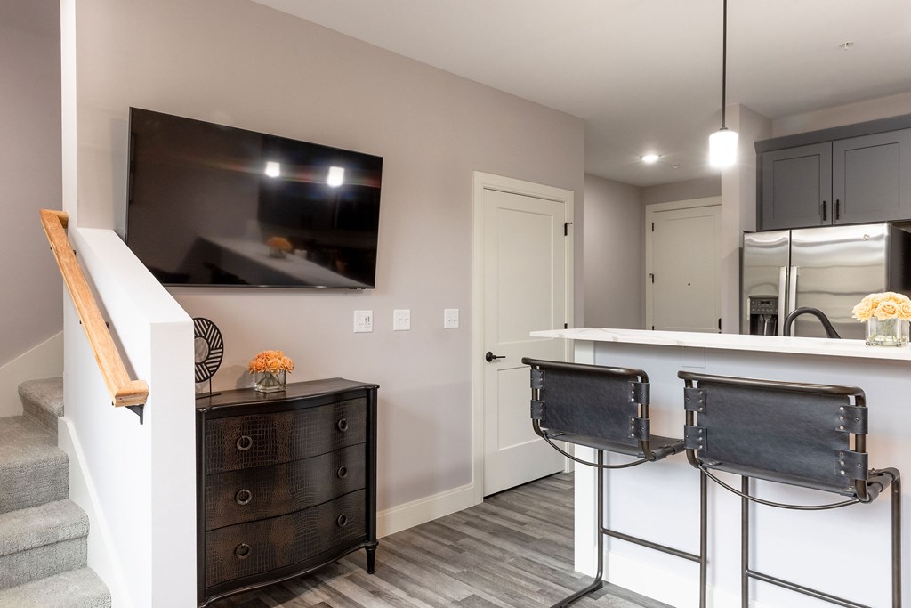 A black dresser with a wooden top sits in a room with a bar and a television mounted on the wall.