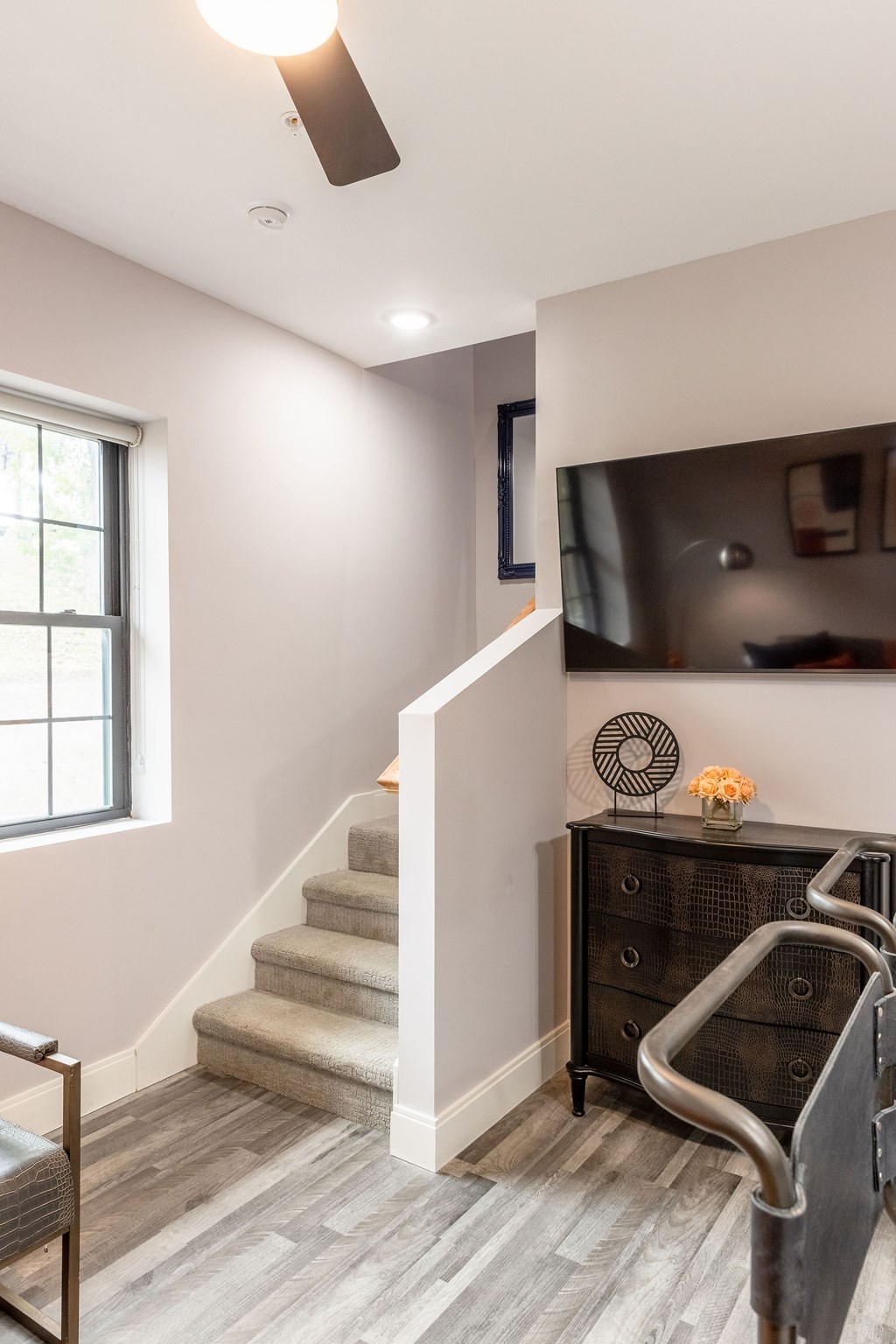 A room with a staircase, a dresser, and a ceiling fan.