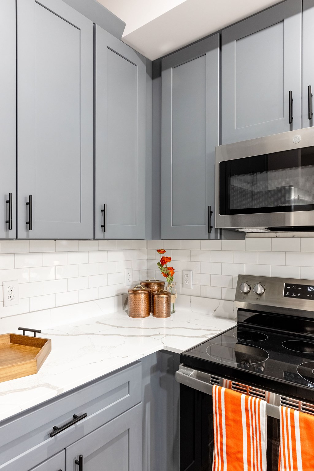 A kitchen with grey cabinets and a black stove top.