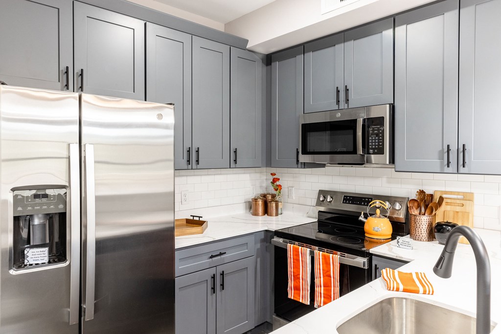 A modern kitchen with a stainless steel refrigerator and a microwave above the stove.