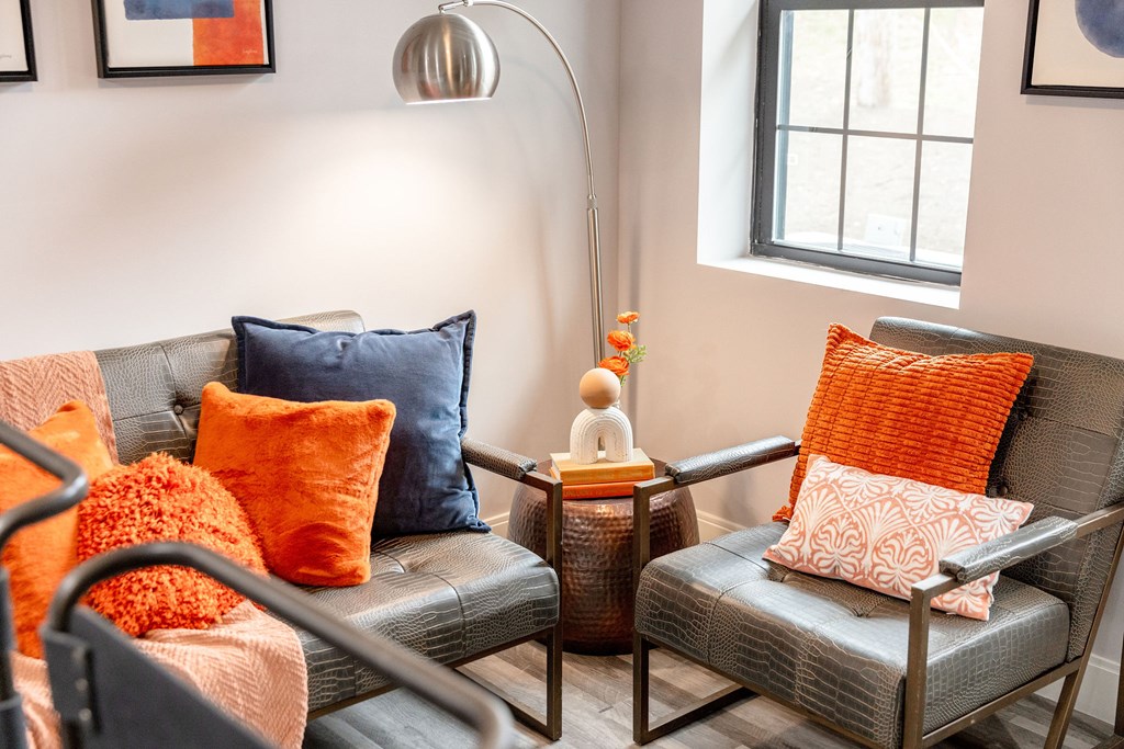 A living room with a grey couch, orange pillows, and a wooden side table.