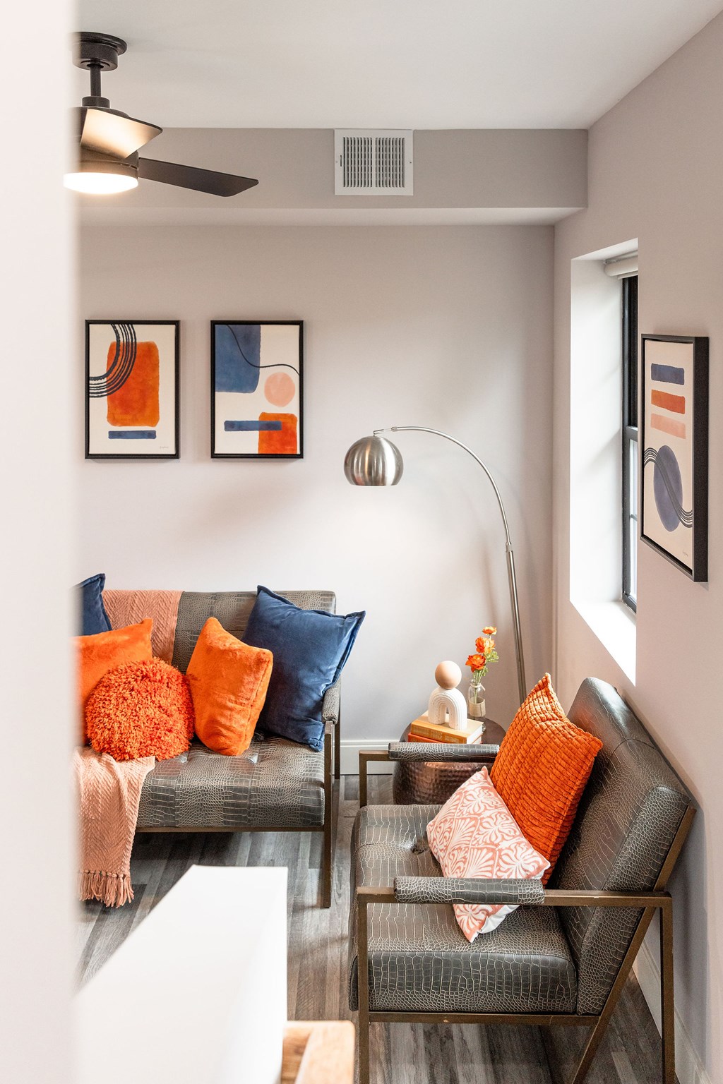 A living room with a grey couch and orange pillows.