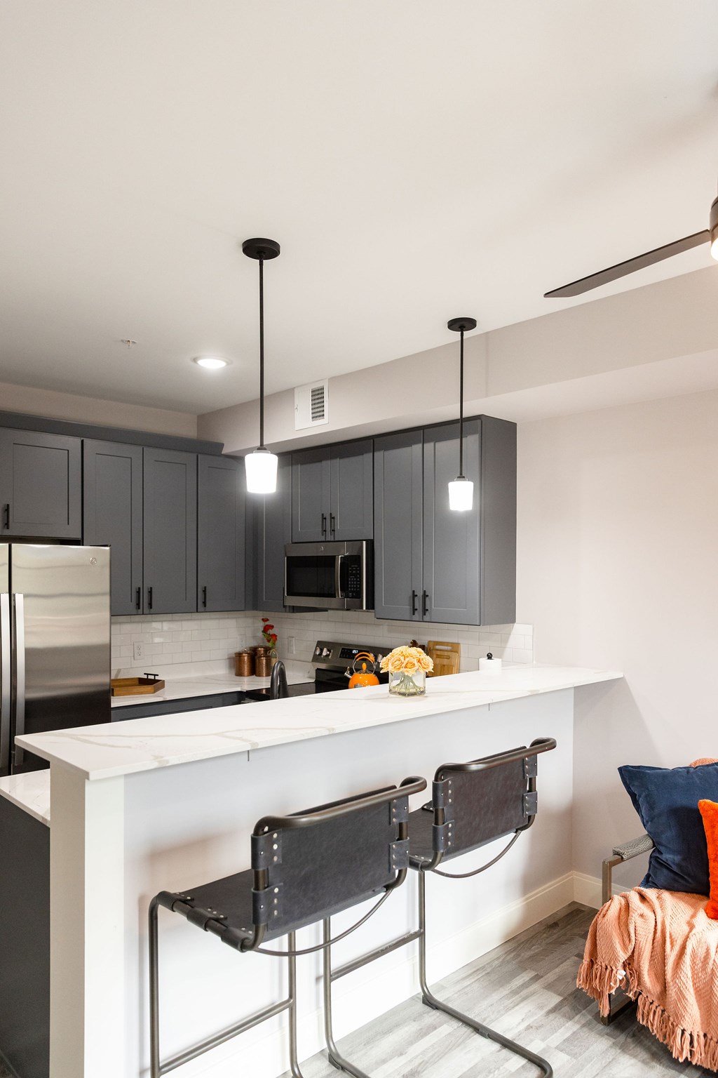 A kitchen with a white counter top and black chairs.
