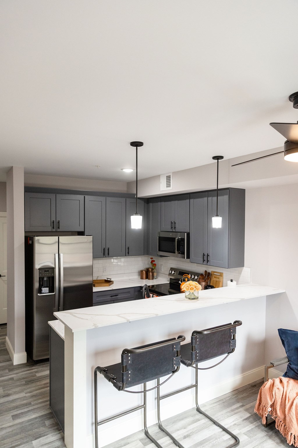 A kitchen with a white counter top and grey cabinets.
