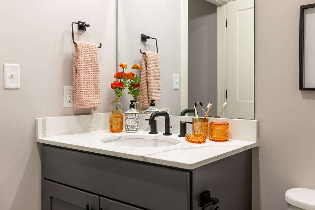 A bathroom with a sink, mirror, and towel racks.