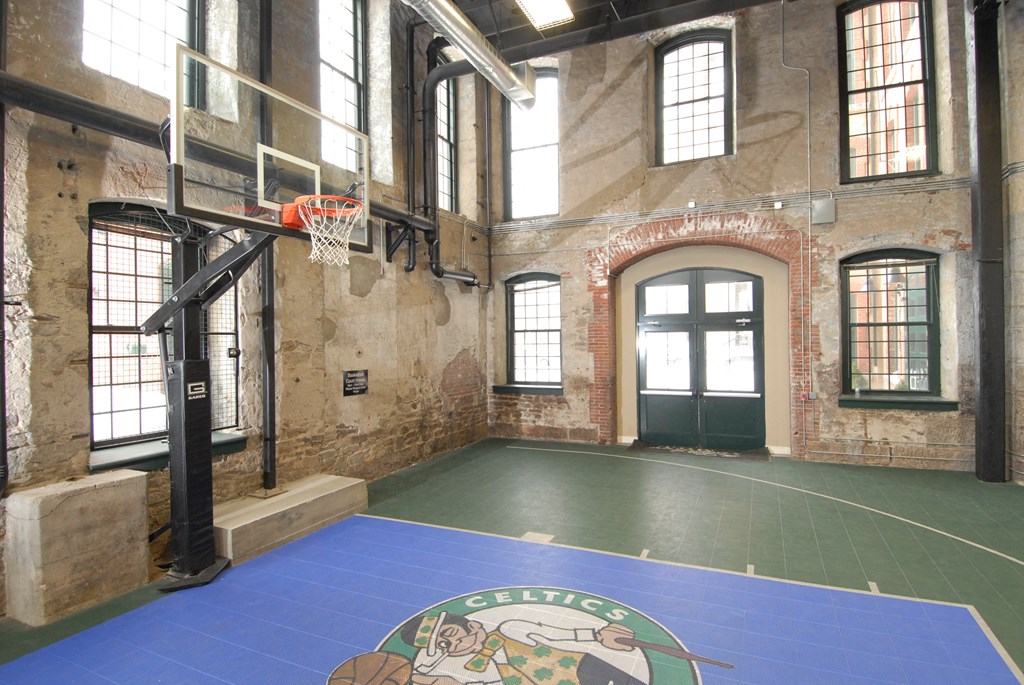 an indoor basketball court in a brick building with a basketball hoop