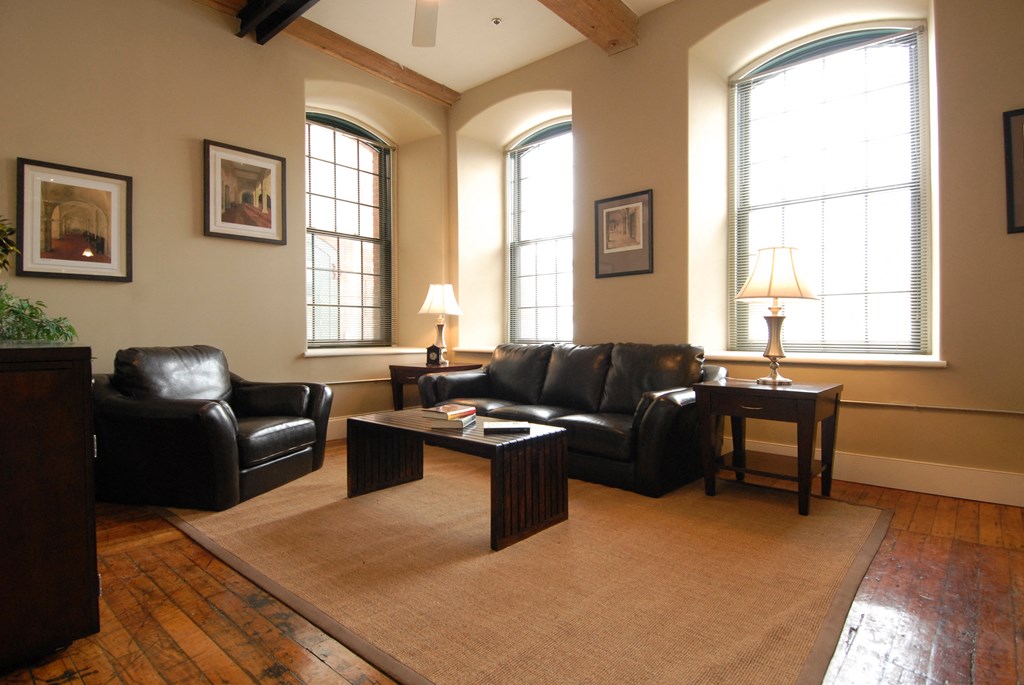 a living room with leather furniture and three windows