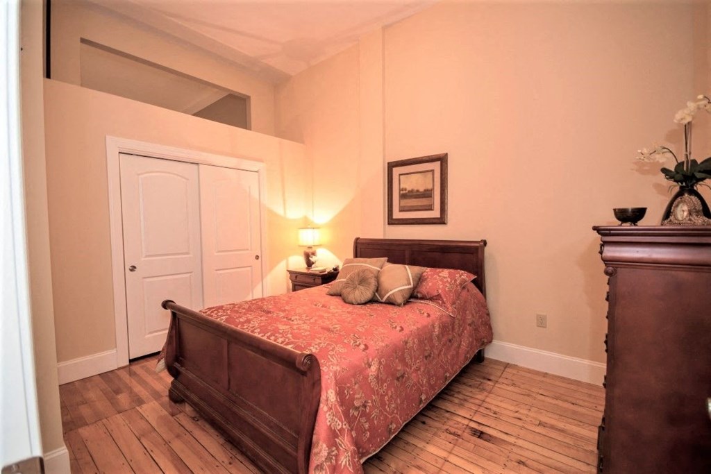 a bedroom with a bed and a wooden floor