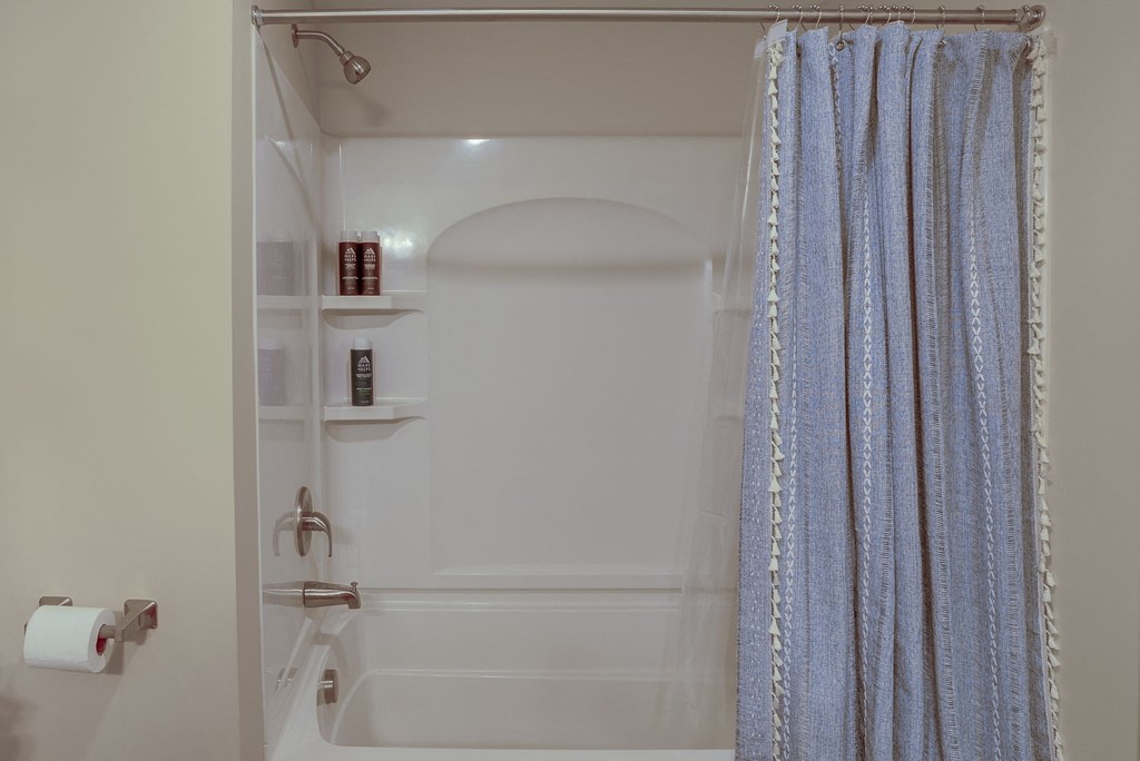 a bathroom with a shower and a blue shower curtain