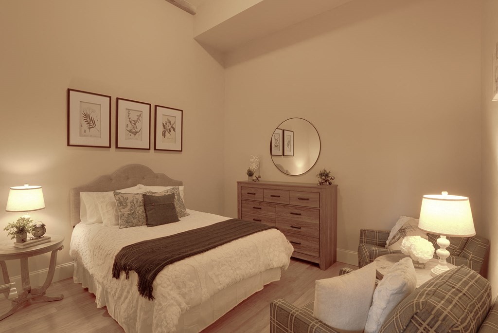 a bedroom with a bed and a chair and a mirror