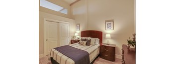 A bedroom with a bed, nightstand, and a plant on the table.