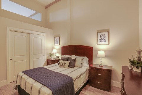 A bedroom with a bed, nightstand, and a plant on the table.