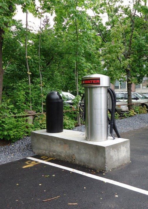 a gas pump and a trash can in a parking lot