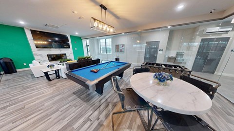 A pool table is in the middle of a room with a marble table and a bar.