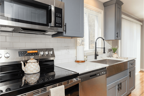 A modern kitchen with a black stove top and a black microwave above it.