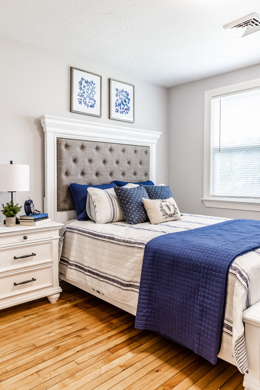 a bedroom with a bed and a dresser with a lamp on it