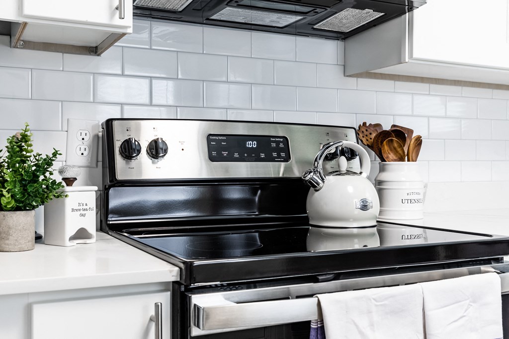 a kitchen with a stove top oven next to a counter top with a kettle on it