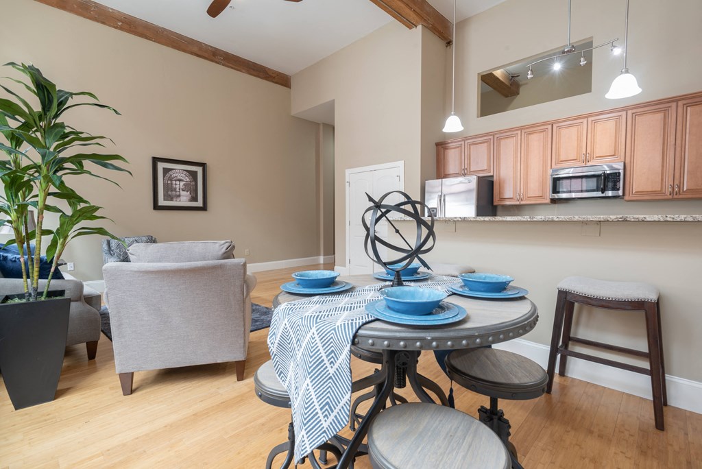 a dining area with a table and chairs and a kitchen in the background