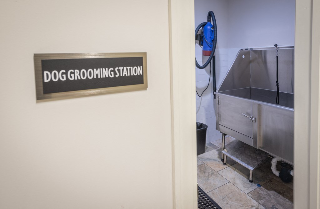 a dog grooming station sign on the wall of a room with a stainless steel sink