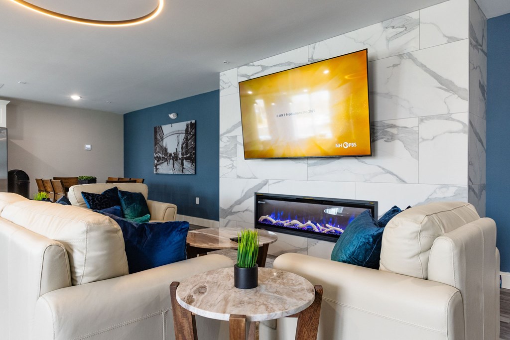 A living room with a white couch, a coffee table, and a flat screen TV mounted on the wall.