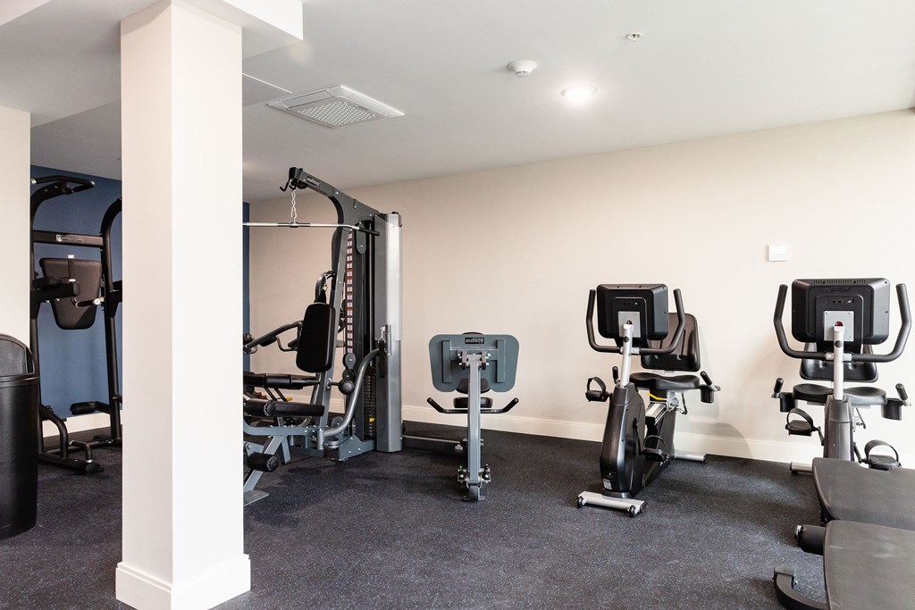 A gym with a row of exercise bikes and a weight machine.