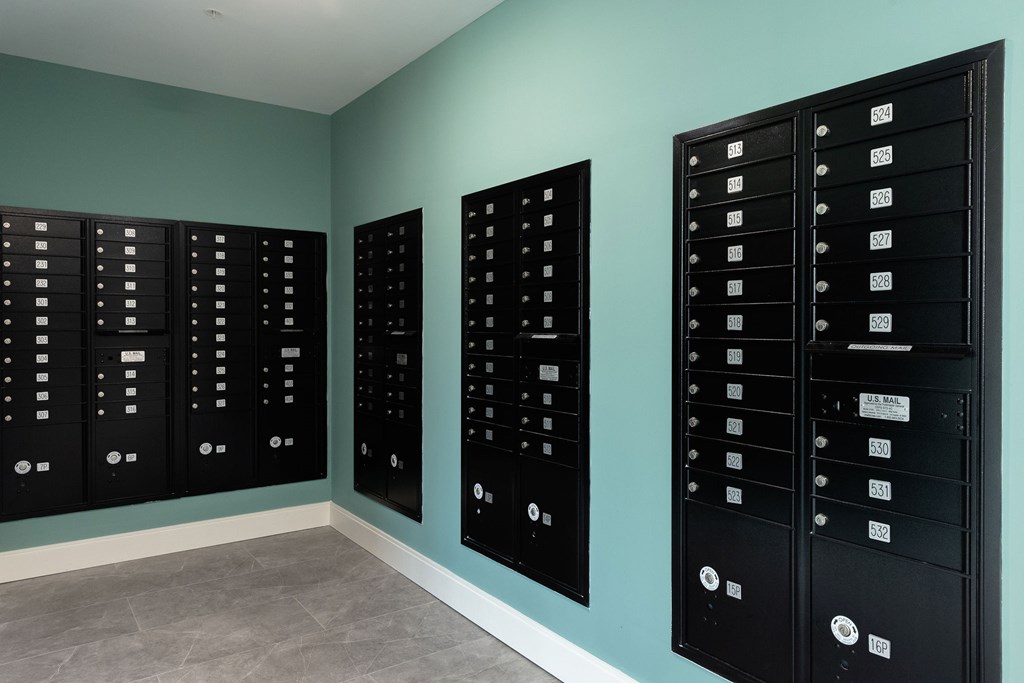 Three black mailboxes on a wall.