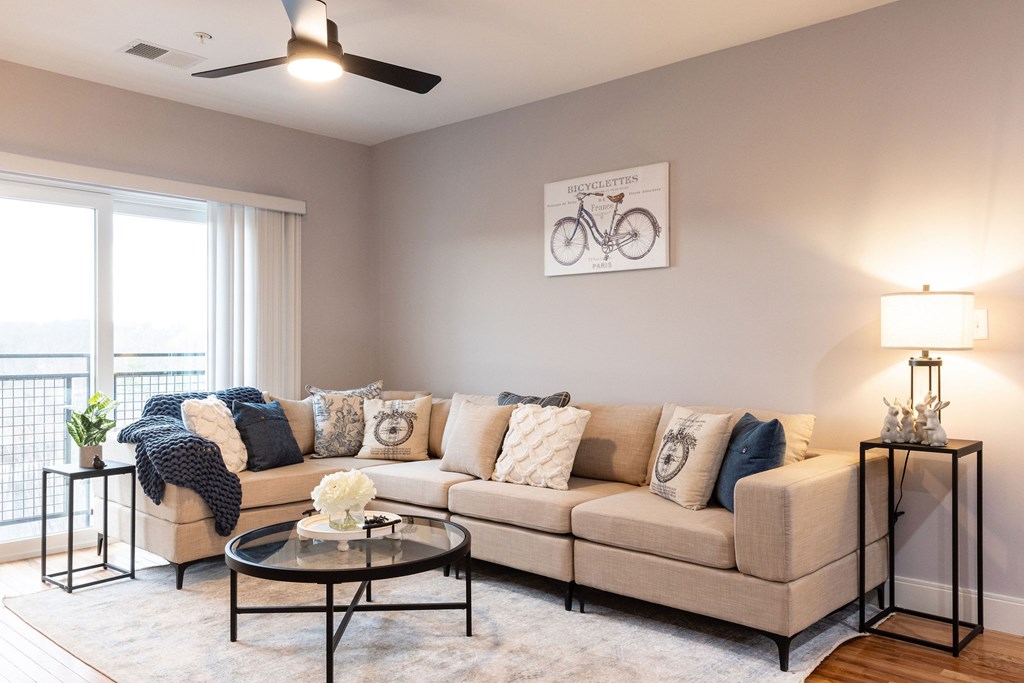 A living room with a beige couch, a coffee table, and a bicycle picture on the wall.