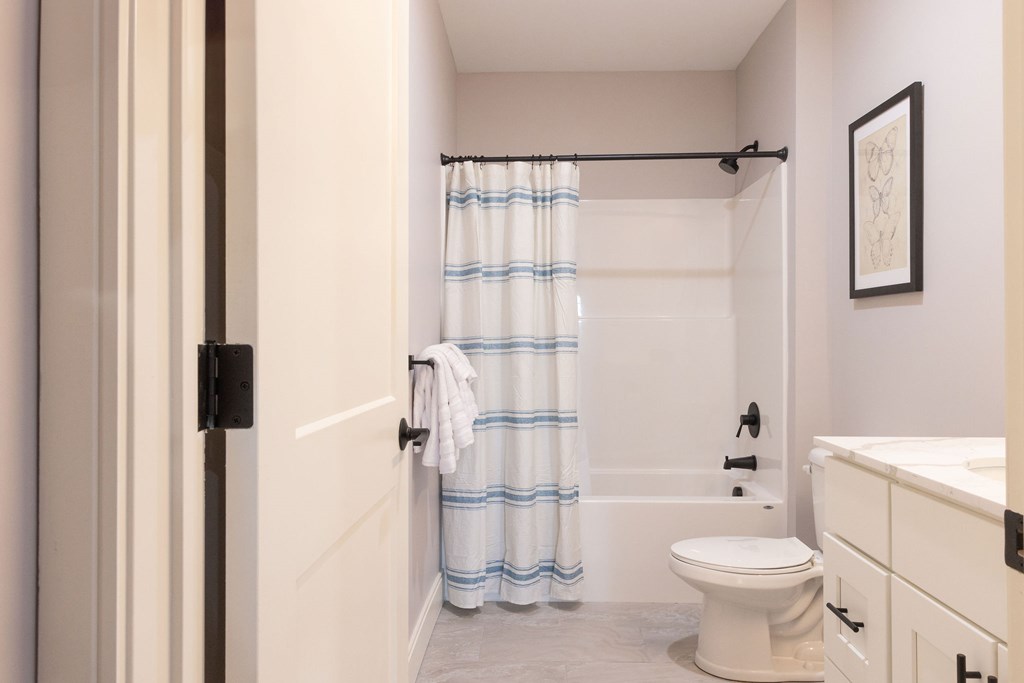 A white toilet sits in a bathroom next to a shower curtain.