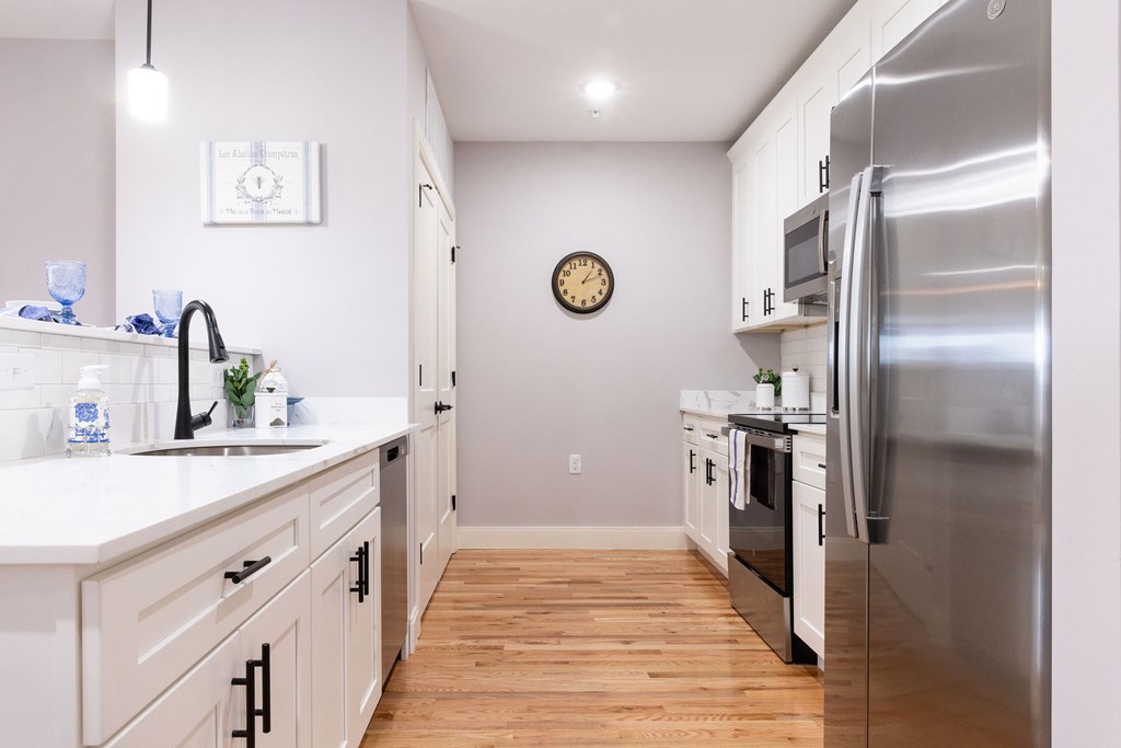 A kitchen with a stainless steel refrigerator and wooden floors.