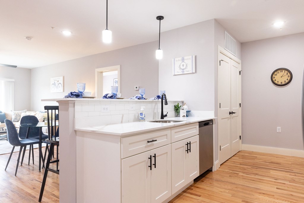 A kitchen with white cabinets and a wooden floor.