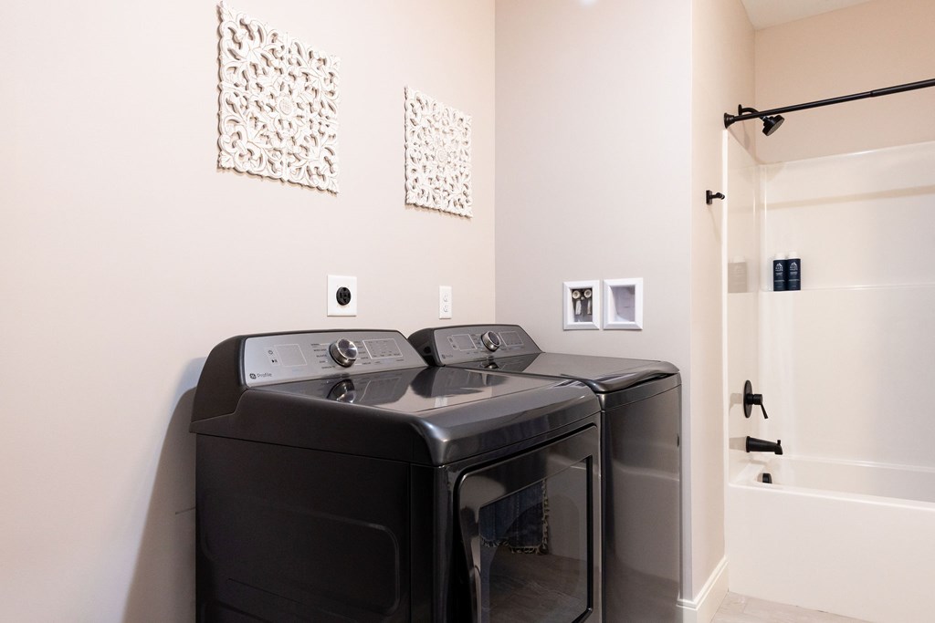 A black washing machine and dryer in a white laundry room.
