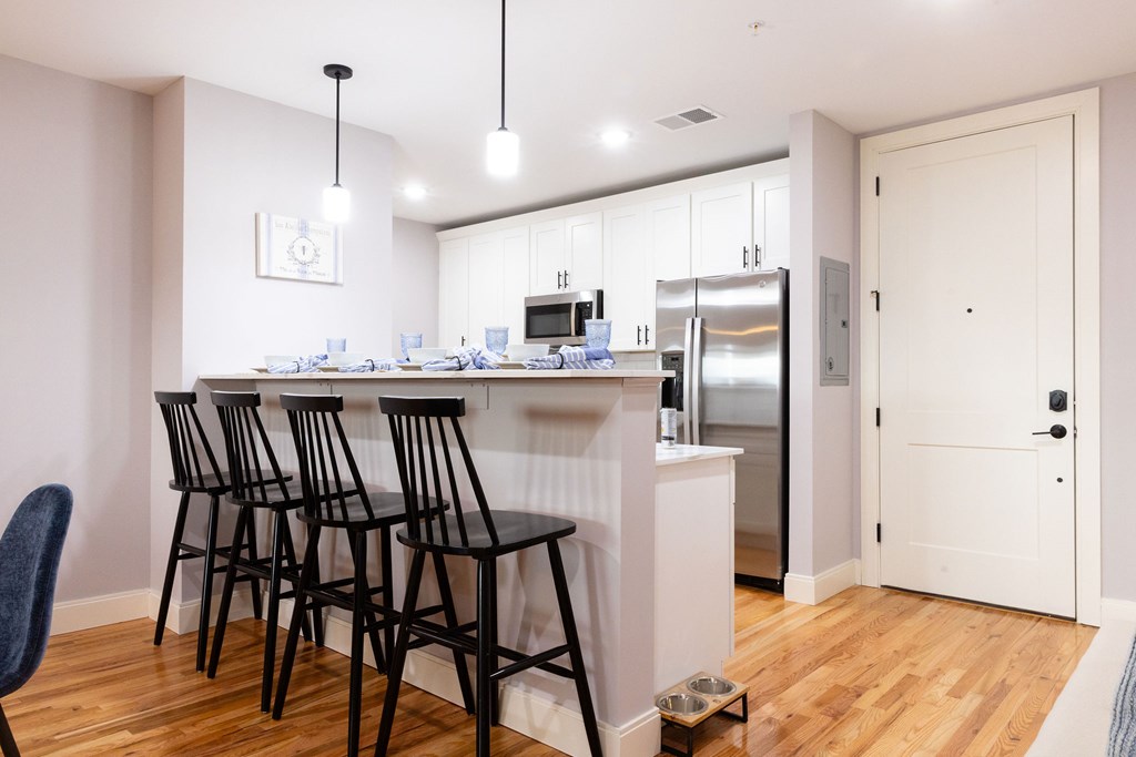 A kitchen with a white counter and black chairs.