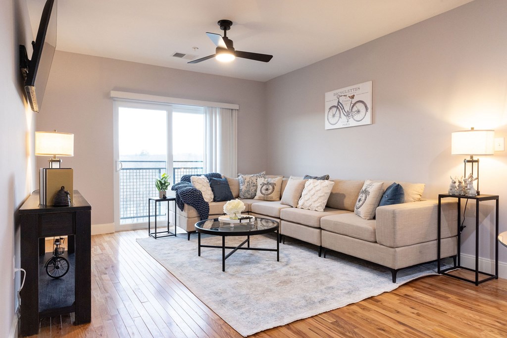 A living room with a beige couch, a black coffee table, and a bicycle picture on the wall.