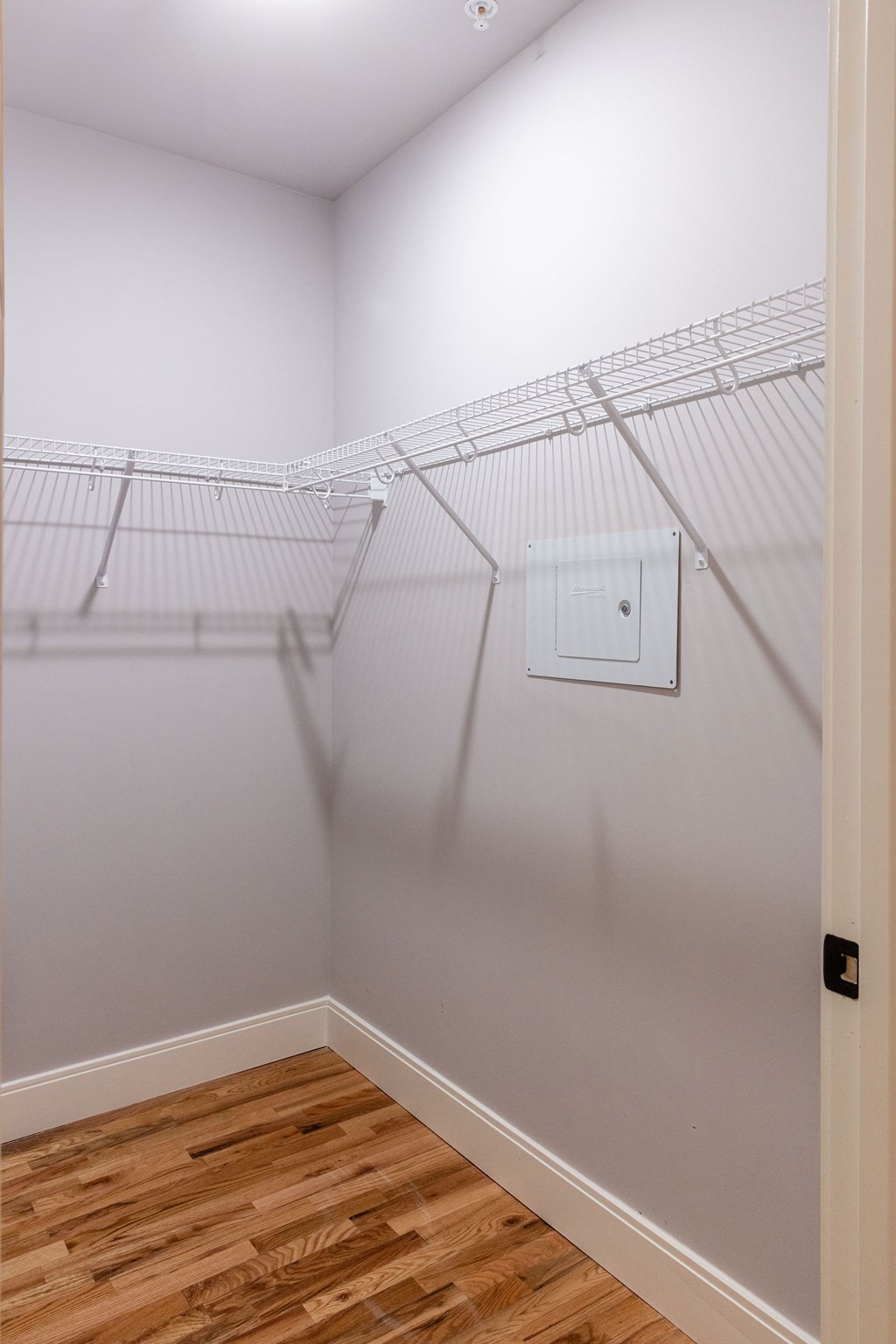 A white wall with a white door and a white electrical outlet.