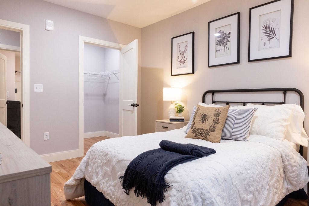A bedroom with a bed, nightstand, and three framed pictures on the wall.
