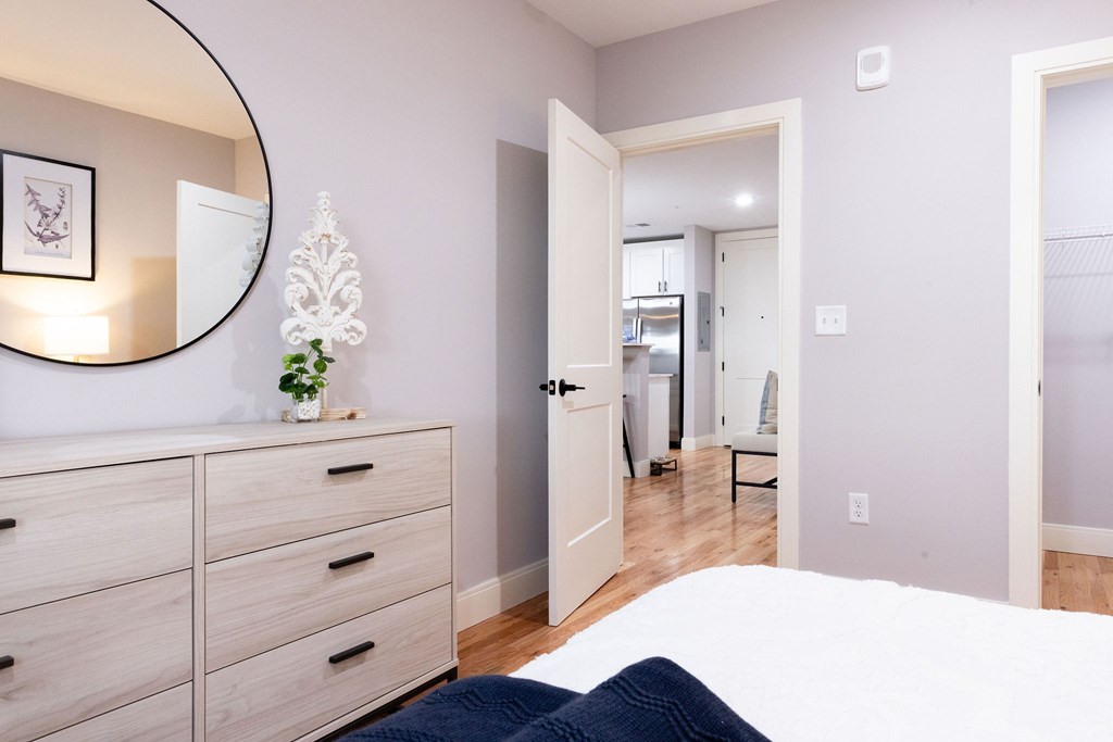 A bedroom with a bed, dresser, and mirror.