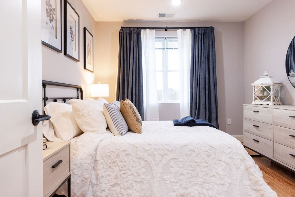 A bedroom with a large bed and a window with curtains.