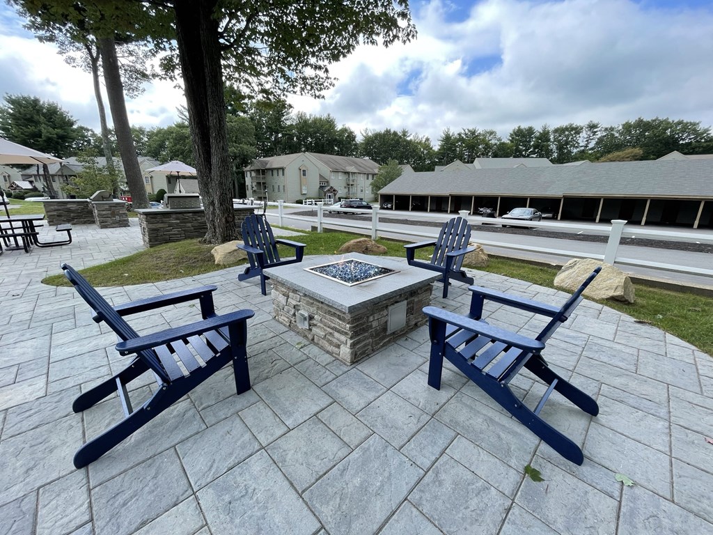 a patio with blue chairs and a fire pit