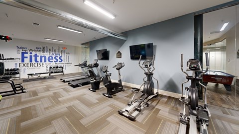 A gym with a variety of exercise equipment including treadmills, stationary bikes, and weight machines.