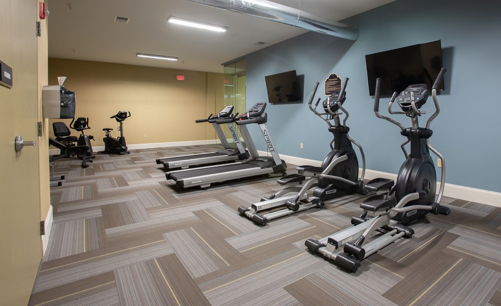 a gym with treadmills and weights and a tv
