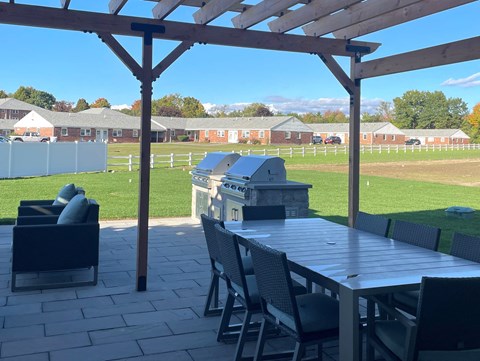 a patio with a table and chairs and a grill