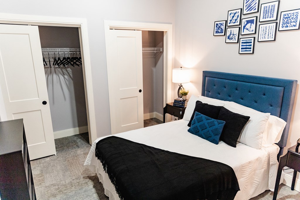 a bedroom with a large bed with a blue headboard and black and white bedding