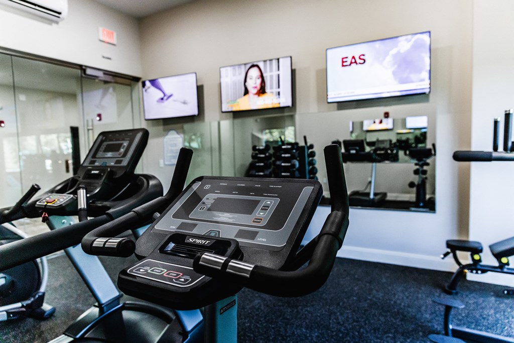 a room filled with cardio equipment and flat screen televisions