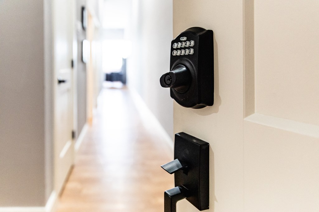 an open door with a coded lock on the door and a hallway in the background