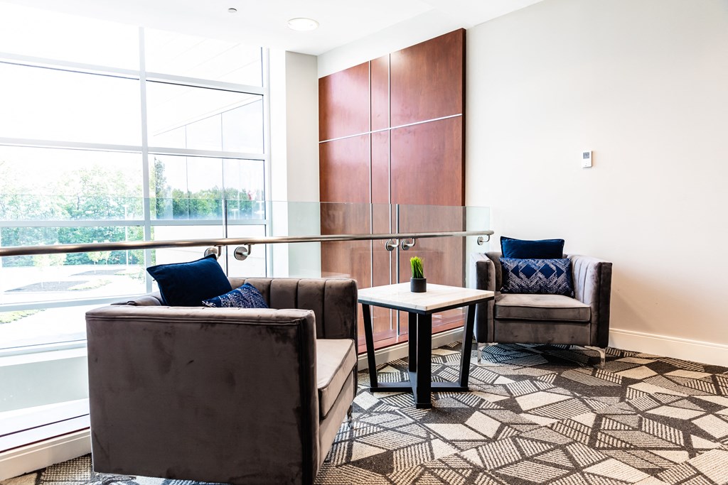 a meeting room with two brown chairs and a table with a vase on it
