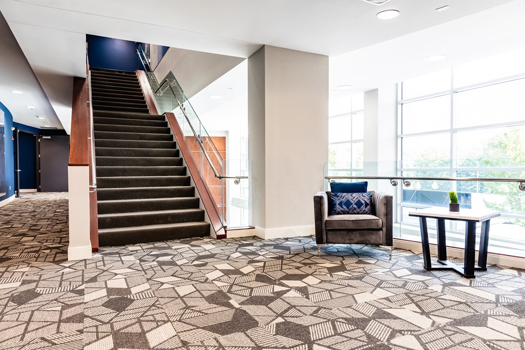 a stairwell in a building with a brown chair and a table with a vase on