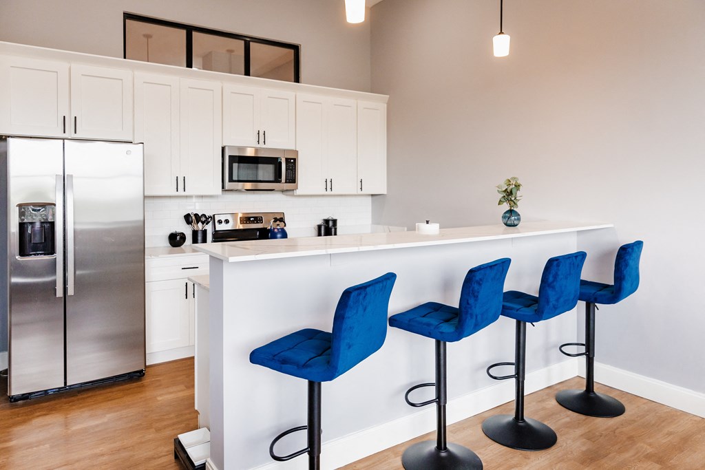 a kitchen with white cabinets and a white island with blue bar stools