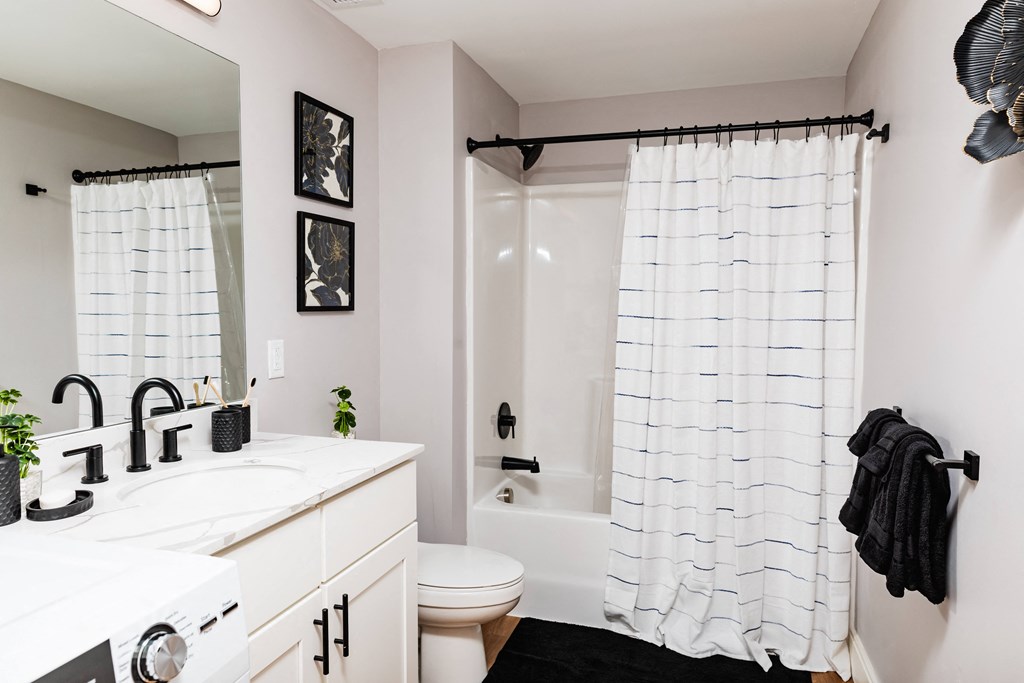 a bathroom with a white sink and toilet next to a white bathtub with a shower curtain