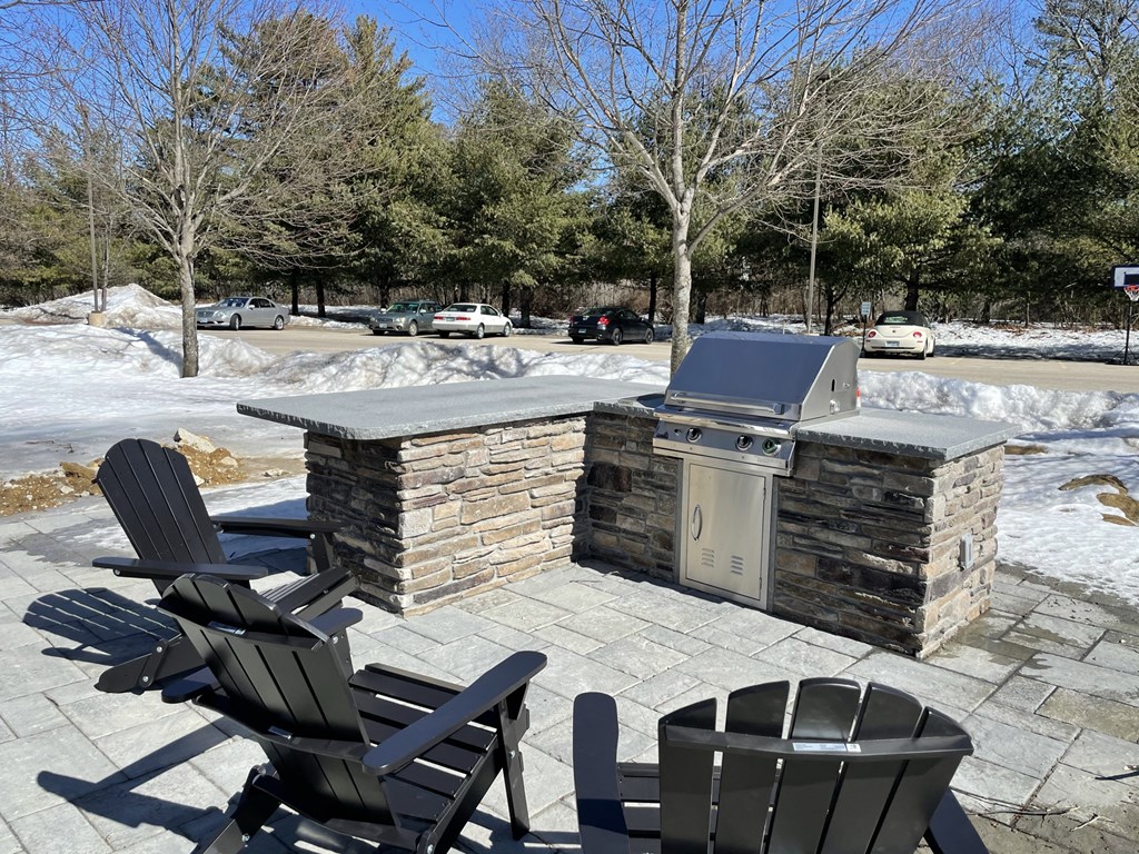 a patio with a grill and chairs in the snow