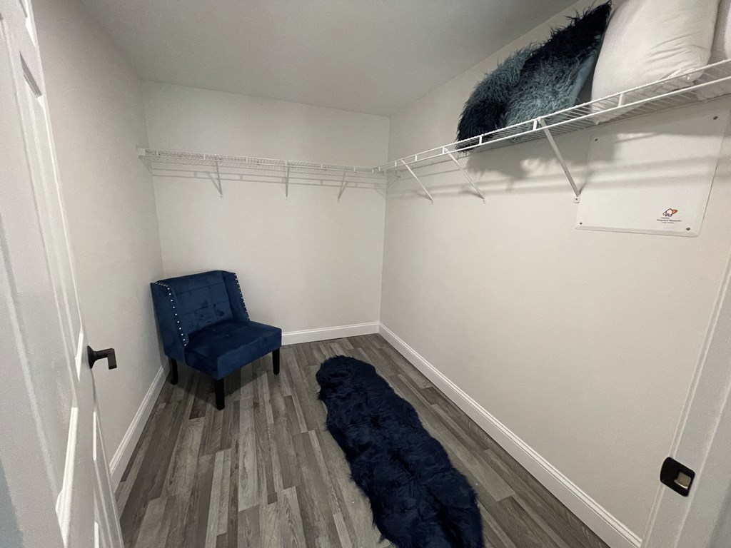 a room with a blue chair and a white wall with a closet and a bed